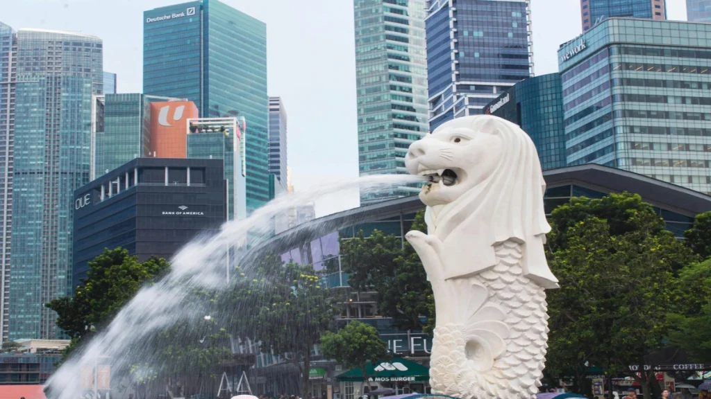 The iconic Merlion statue spouting water in Singapore, set against a backdrop of modern skyscrapers. This image represents a key visual for understanding Singapore's country profile and economic identity.